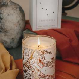 Lit candle in a glass jar with a decorative label