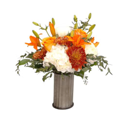 Orange and white floral arrangement in a tall metal vase