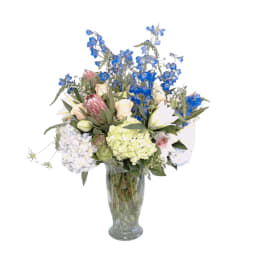 Mixed bouquet of blue and pastel flowers in a clear glass vase