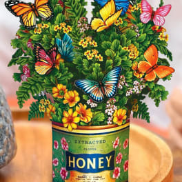 Butterfly-themed floral arrangement in a honey can container