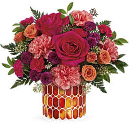 Bouquet of pink and orange flowers in a patterned glass vase