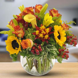 Bouquet of sunflowers, roses, and calla lilies in a glass vase
