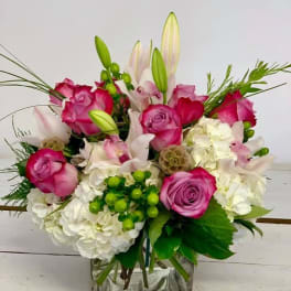 Pink roses and white lilies in a square glass vase