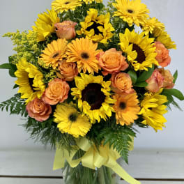 Bouquet of yellow sunflowers and peach roses in a glass vase