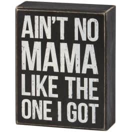 Black wooden sign with white text reading "AIN'T NO MAMA LIKE THE ONE I GOT"