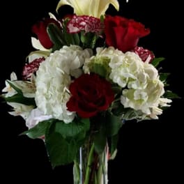 Bouquet of red roses, white hydrangeas, and white lilies in a clear vase