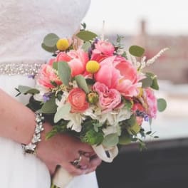 Bride holding a pink and white bouquet with greenery