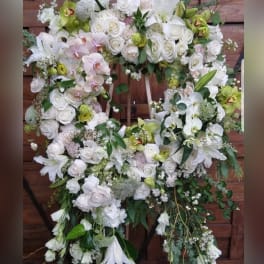Large floral wreath of white roses, orchids, and lilies on an easel
