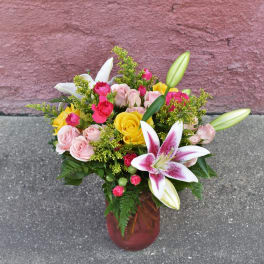 Bouquet of pink and yellow roses with lilies in a glass vase