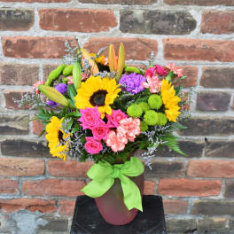 Colorful bouquet with sunflowers, roses, lilies, and carnations in a vase