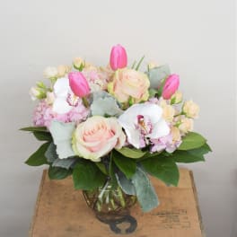 Pink and cream bouquet with roses, tulips, orchids, and hydrangea in a glass vase