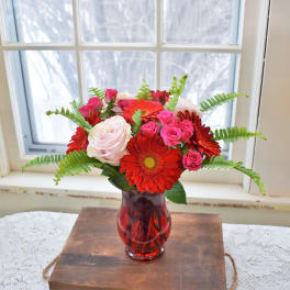 Bouquet of red and pink flowers in a red glass vase