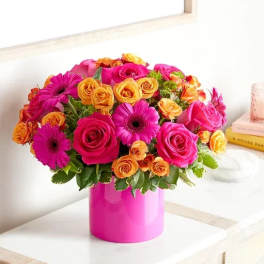 Pink and orange mixed flower arrangement in a bright pink vase