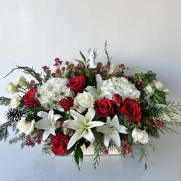 Red and white rose arrangement with lilies and hydrangeas in a low container