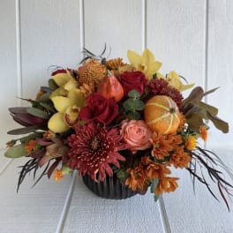 Autumn floral arrangement in a black pumpkin vase with roses and mums