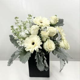 White roses and gerbera daisies in a black vase