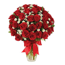 Bouquet of red roses and white daisies in a glass vase with a red ribbon