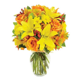 Yellow lilies and orange roses in a clear glass vase