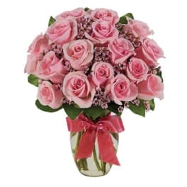 Pink roses arranged in a clear glass vase with a pink ribbon
