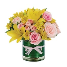 Pink roses and yellow lilies in a glass vase with a ribbon