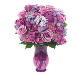 Pink and purple mixed bouquet in a purple glass vase