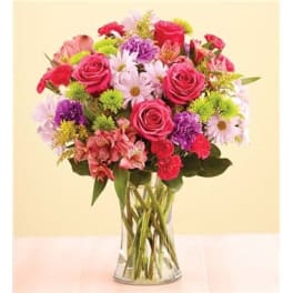 Mixed bouquet of pink roses, daisies, and carnations in a clear glass vase