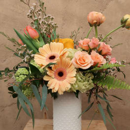 Peach and pink mixed bouquet in a white textured vase