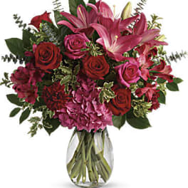 Bouquet of pink lilies and red roses in a clear glass vase