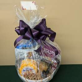 Gift basket with assorted snacks wrapped in clear cellophane and a purple bow