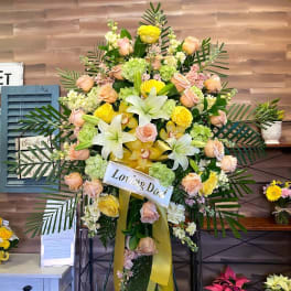 Standing sympathy spray with roses, lilies, and orchids on an easel