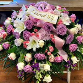 Large pink and white floral spray with a ribbon reading Beloved Wife