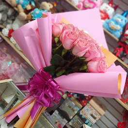 Pink rose bouquet wrapped in pink paper with a purple ribbon