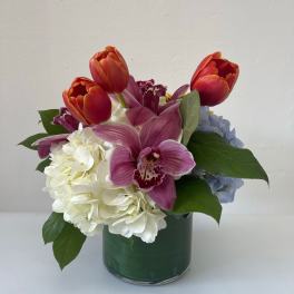 Mixed bouquet with tulips, orchids, and hydrangeas in a glass vase
