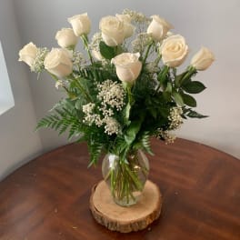 White roses arranged in a clear glass vase with baby's breath