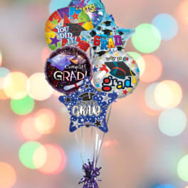 Cluster of graduation-themed balloons with a purple weight at the bottom