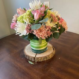 Mixed bouquet of pink, white, and peach flowers in a green striped vase