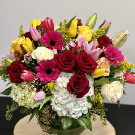 Mixed bouquet of roses, tulips, gerbera daisies, lilies, and hydrangea in a glass vase