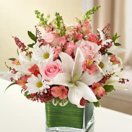 Pink and white floral arrangement in a square glass vase