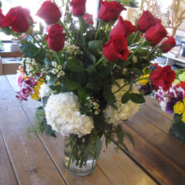 Red roses in a clear glass vase with white hydrangeas