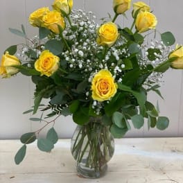 Yellow roses in a clear glass vase with white baby's breath