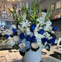 Large blue and white floral arrangement in a white vase