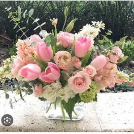 Pink tulips and roses arranged in a clear glass vase