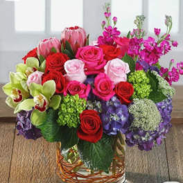 Mixed bouquet of roses, orchids, and hydrangeas in a glass vase