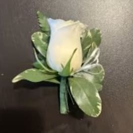 White rose boutonniere with green leaves