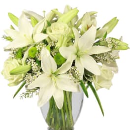 White lilies and roses arranged in a clear glass vase