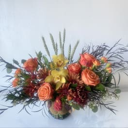 Orange roses and yellow orchids in a low decorative vase