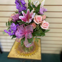 Bouquet of pink roses, purple flowers, and a pink lily with a ribbon