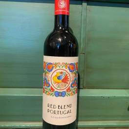 Bottle of red wine with a colorful label on a green wooden surface
