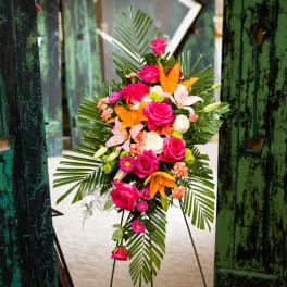 Standing floral spray with pink roses, lilies, and palm fronds