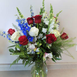 Red roses and white flowers in a clear glass vase